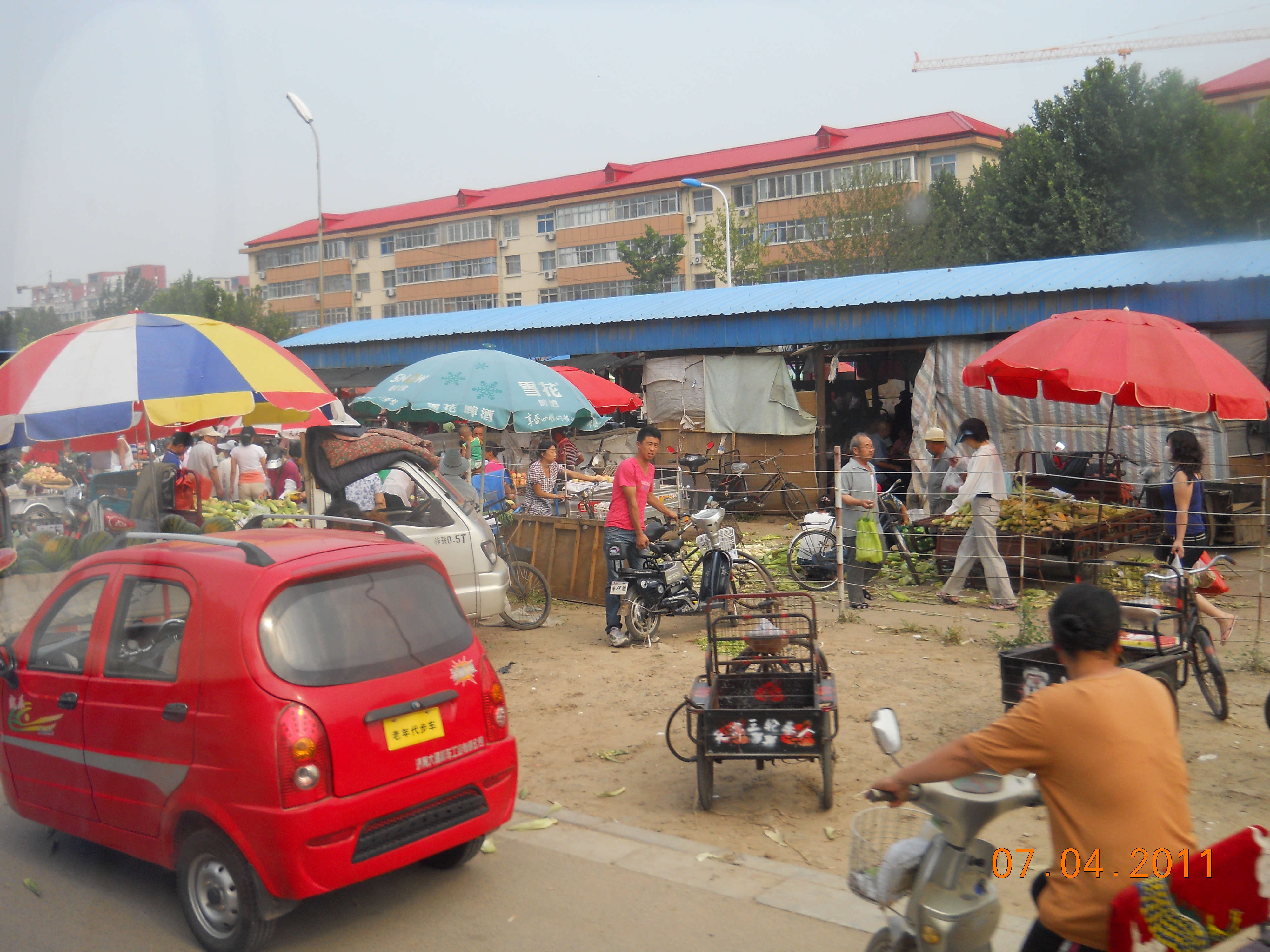 Selling vegetables and fruit on the streets with new construction in the background.